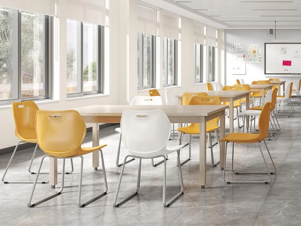 Classroom with rectangular shared tables and loose yellow and white student chairs