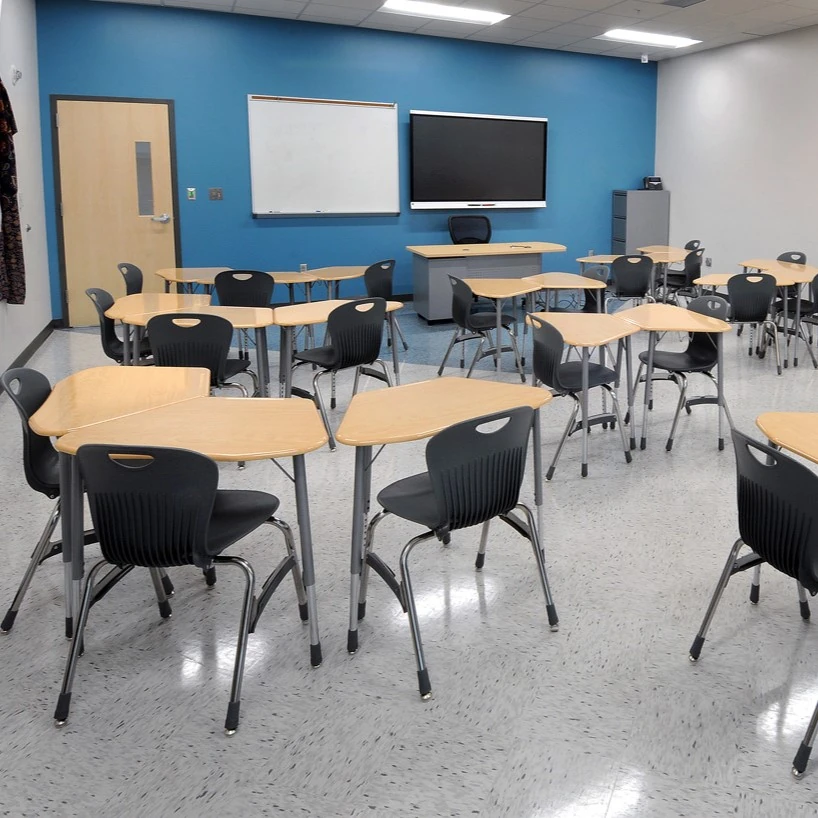 Classroom with shaped individual student desks, black chairs and a teaching wall